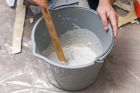 Mixing white plaster in a bucket with a stirrer. Close-up.の写真素材