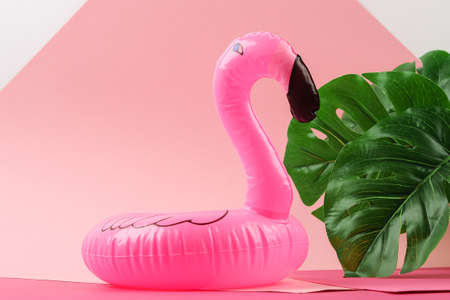 Inflatable pink mini flamingo and tropical leaf monstera on pink background. Summer background. Creative summer beach concept. Flamingo Trend Inflatable Toy.の写真素材