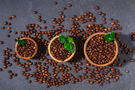 Roasted brown coffee beans on a gray background. Coffee beans in wooden bowls. Top view.の写真素材