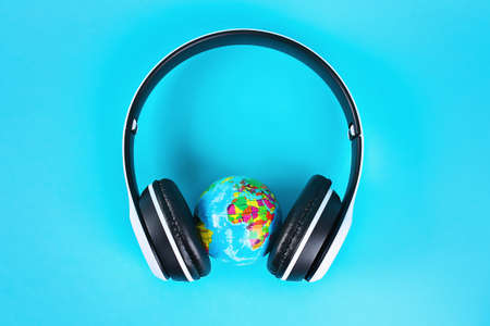 Globe in white wireless headphones on a blue background. Concept for an international day of music.の写真素材