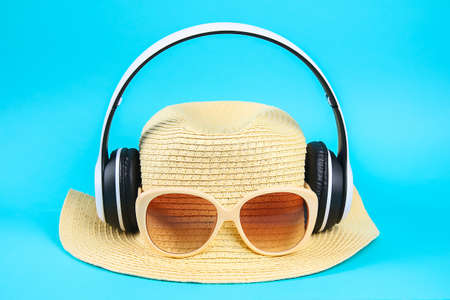 Hat in sunglasses in white wireless headphones on a blue background. The concept of rest,...
