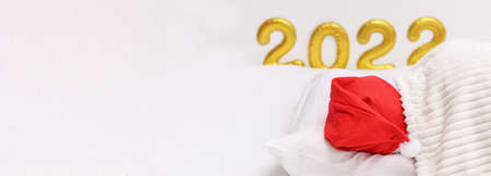 A man sleeps in a Christmas hat against the background Number 2022 written with balloons. New Year 2022.の写真素材