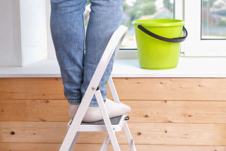 A man stands on a stepladder and washes the window from above. Feet on the stairs. Cleaning, repair.の写真素材