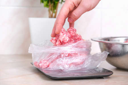 A man lays out portioned pork and beef minced meat on the scales in bags for storage in the freezer.の写真素材