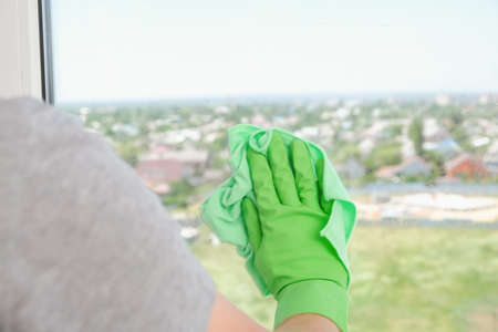 A man washes a glass window and a plastic frame with a folk remedy with household soap. Ecology.の写真素材