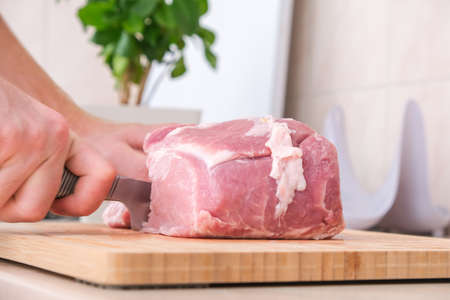 A man cuts meat with a knife on a wooden board. Preparation of minced beef and pork for cutlets, meatballs, chops.の写真素材