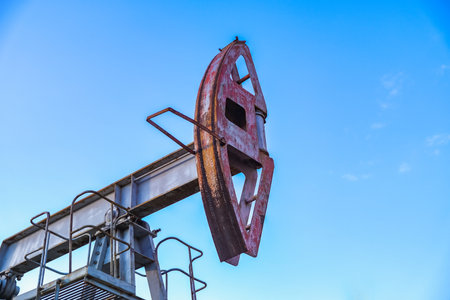 An abandoned oil or gas rocking machine against a blue sky, exhausted resource. A clogged field of gas and oil production.の写真素材