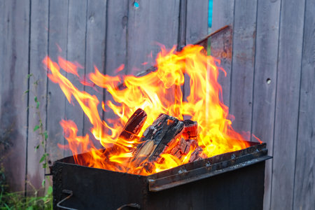 Burning pine logs for coals. Strong flame on the grill. Burning firewood on the grill. The fire is...