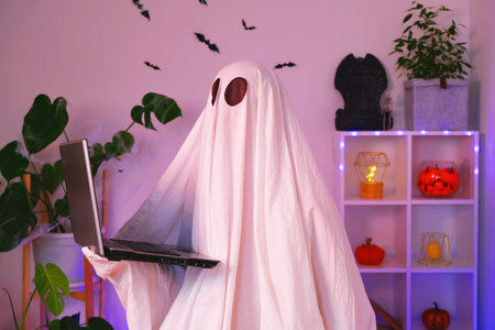 The ghost of Halloween uses a laptop to surf the Internet, to browse online stores, markets. A ghost makes an order computer for Halloween. The ghost pays for an online purchase. Neon light.の写真素材