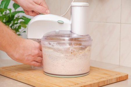 A man grinds pieces of chicken breast with spices, chicken egg, mayonnaise in a food processor. Meat puree in a food processor. The process of cooking chopped chicken cutlets.の写真素材