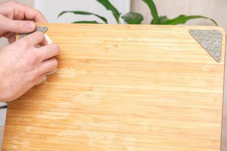 A man wipes a bamboo cutting board with a white paper napkin after washing with water. Careful handling of wood products. Bamboo cutting board. Treatment with mineral oil. Drying of the cutting board.の写真素材