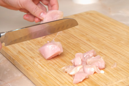 Defrosted raw chicken fillet on cutting board. Slicing fresh raw chicken breast with sharp knife for cooking chopped chicken cutlets on a bamboo wooden cutting board for slicing. Kitchen knife test.の写真素材