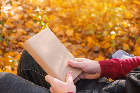 A man holds a book with an empty space in the autumn nature. Book copy space. The concept of reading...