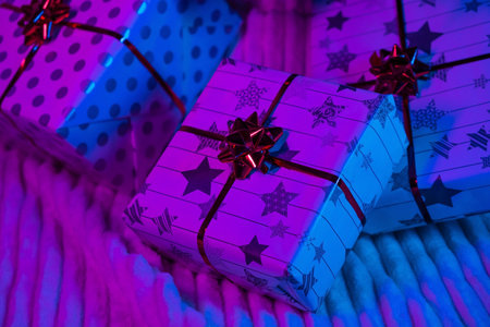 Gifts Christmas in neon light. Wrapped in wrapping paper and bows boxes. New Year 2023. Merry Christmas. Shopping.の写真素材