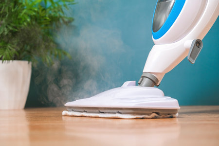 A man washes the floors with a steam mop. Floor treatment with hot steam. Hygienic control of cleanliness.の写真素材
