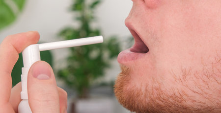 An adult male uses a throat spray to relieve sore throat. The concept of medicine, health.の写真素材