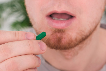 A young man takes out a tablet, a pill from a blister pack. The concept of health, medicine.の写真素材
