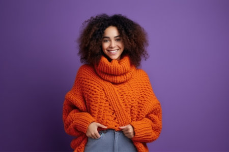 A girl with curls in an orange sweater on a solid purple background.の素材