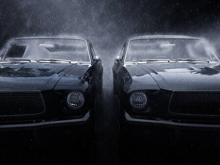 Two awesome black vintage muscle cars side by side in the rainの写真素材