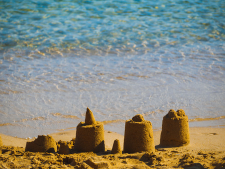 Small sand castles near water on a small beach in Greece