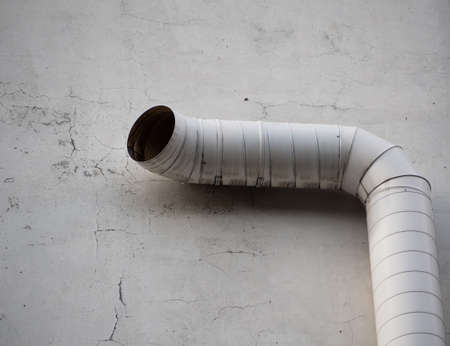 Big white external ventilation pipe up against concrete wallの写真素材