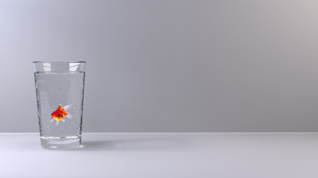 Small gold fish in a glass of fresh clear waterの写真素材