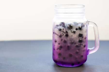 Beautiful frozen purple jar shaped mug full of ripe juicy fresh berries on a background of pastel...