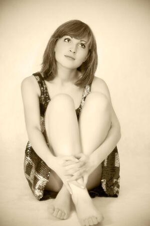 Young beautiful woman sitting on floor, sepia tonedの写真素材