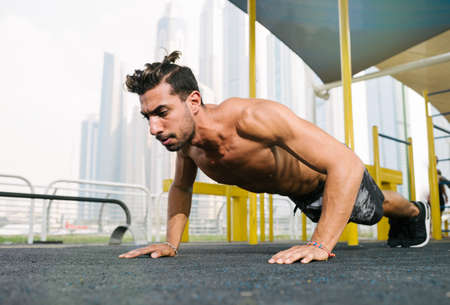 Young muscular arab athlete doing pushups otdoors in Dubai.