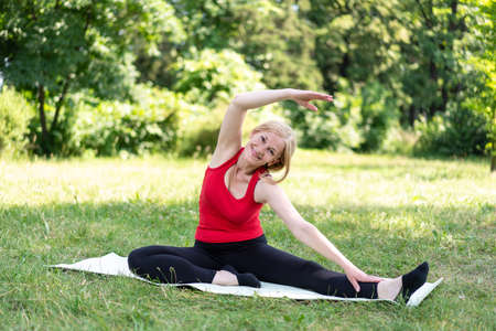 50 years old woman in a red top training outdoors.の写真素材