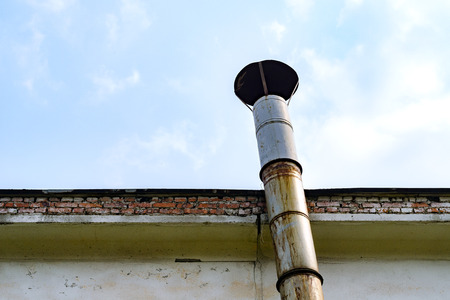 Industrial Chimney Pipe Along A Brick Wall Against The Blue Skyの写真素材
