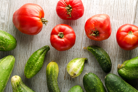 Healthy Food Background. Fresh Cucumbers and tomatoes on a wooden white table. Top view.の写真素材