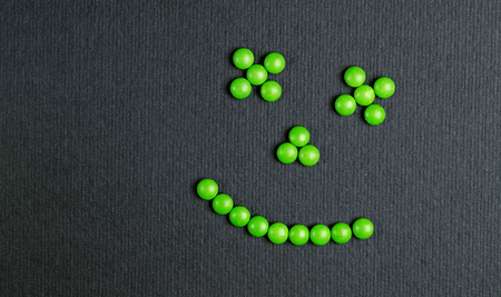 Green Tablets Or Drugs In The Form Of A Circular Shape Of A Smile On A Black Background.の写真素材