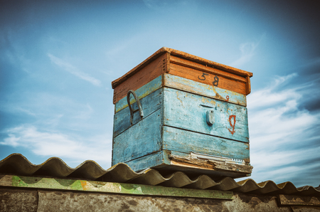 Wooden Beehive On The Roof Of A Barn On A Background Of Blue Sky. Vintage, Grunge Version.の写真素材