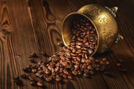 Roasted Coffee Beans (Arabica) In A Gold Metallic Cup On A Wooden Board. Background Series. Shallow Depth Of Field.の写真素材