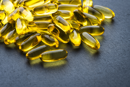 Omega 3 Gelatin Capsules Scattered On A Gray Slate Background. Fish Oil, Vitamins, Pills. Medical Series. Close Up. Macro. Angle View.の写真素材