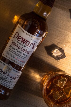 UFA, RUSSIA - JANUARY 28, 2019: Bottle Of Dewars And A Glass Of Whiskey With Ice. Brand's White...