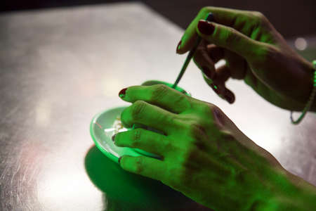 Green light on hands stirring coffeeの写真素材