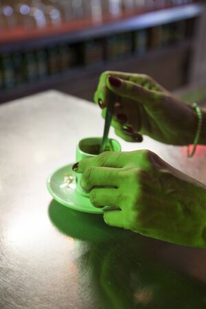 Green light on hands stirring coffeeの写真素材