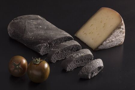 Black bread with vegetal carbon, black tomatoes and cheeseの写真素材
