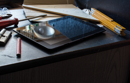 Tablet On A Dark Cupboard Surrounded by Tools In A Dirty Basement