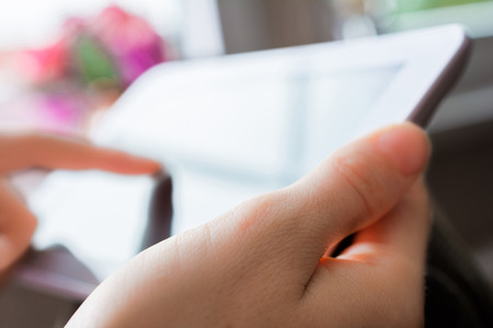 Woman Using Blank Business Tablet In Landscape View Next To A Window