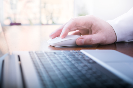 Businessman Working With Mouse And Computer On A Table In Front Of A Bright Windowの写真素材