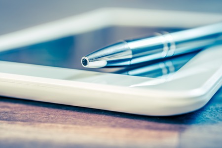 Chrome Pencil Lying On A White Tablet On Wooden Tableの写真素材