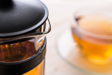 Teapot With A Blurry Cup Of Tea In Backgroundの写真素材