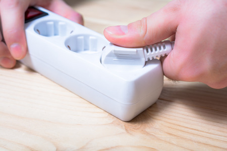 Pulling An Electrical Plug Out Of A Power Strip To Save Power - Power Saving Conceptの写真素材