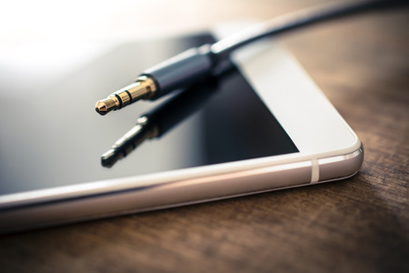 Earphone Cable Plugged Out, Lying On White Smartphone On Woodenの写真素材