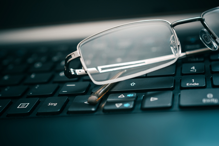 Eyeglasses Lying On Dark Computer Keyboardの写真素材