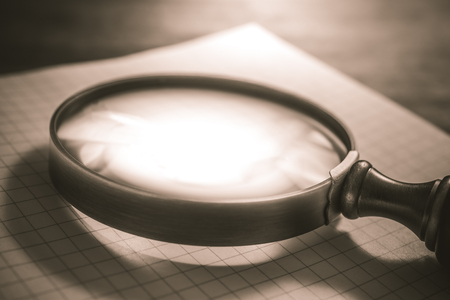 Vintage Loupe Lying On An Open Checkered Diary In Sepia Colorsの写真素材