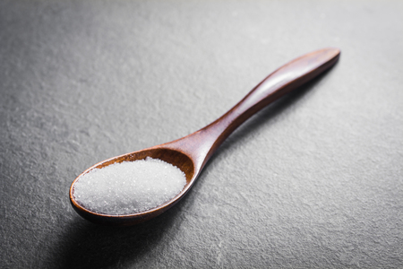 Wooden Spoon With White Grain Sugar On Slate Stone, Side Viewの写真素材